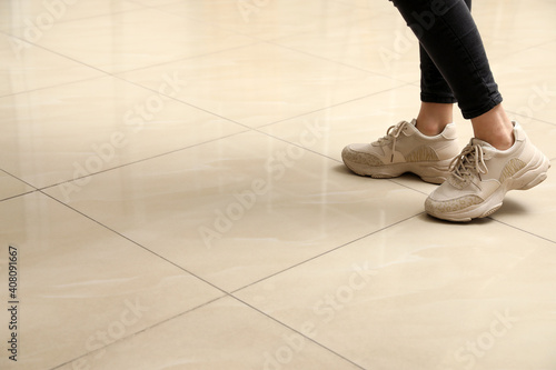 Woman standing on ceramic floor, closeup. Space for text