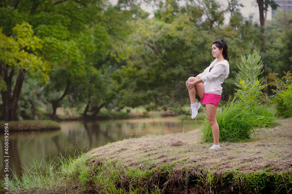 A beautiful Asian woman is warm up, To make the muscles flexible Before going to jogging A beautiful Asian woman is warm up, To make the muscles flexible Before going to jogging