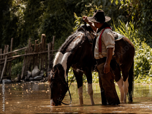 Old cowboy rested with a horse in the stream after he finished showering the horse