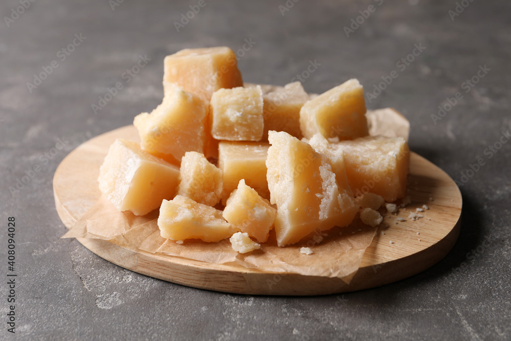 Parmesan cheese with wooden board on grey table, closeup Parmesan cheese with wooden board on grey table, closeup
