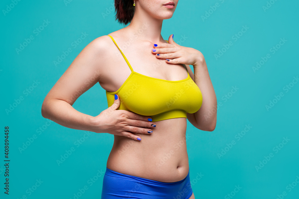 Foto de Woman in yellow top bra with big natural breasts on blue background  do Stock