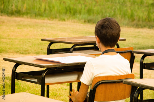 child at school sitting in the table in the park photo