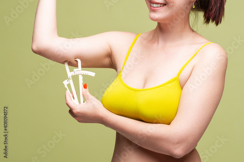 Woman measuring her hand with caliper on light green background photo