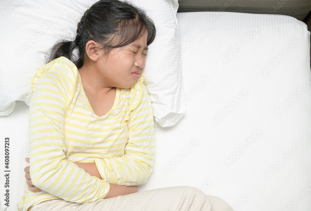 asian girl suffering from stomachache and lying on bed. diarrhea or healthy asian girl suffering from stomachache and lying on bed. diarrhea or healthy