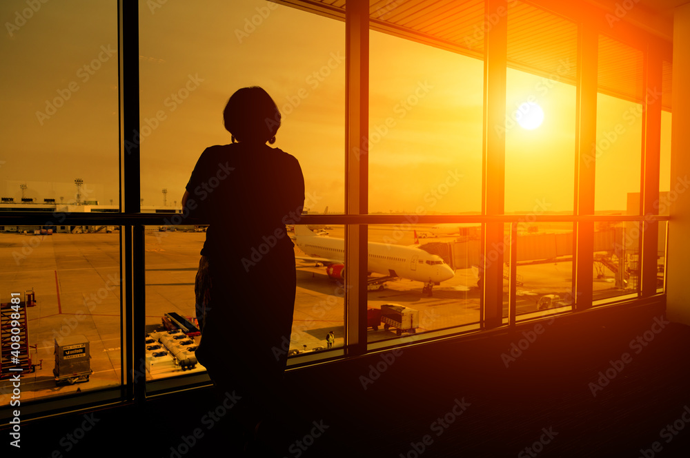 A silhouette of a tourist waiting in an airport with the morning sunlight when a plane failed to fly due to the COVID-19 outbreak