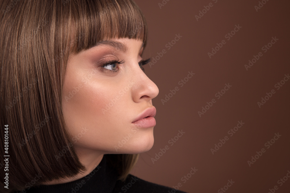 Naklejka premium Portrait of a beautiful brown-haired woman with a short haircut on a brown background
