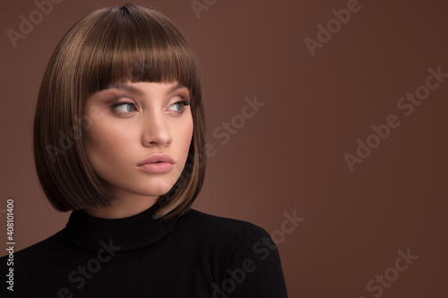 Portrait of a beautiful brown-haired woman with a short haircut on a brown backg Fotobehang
