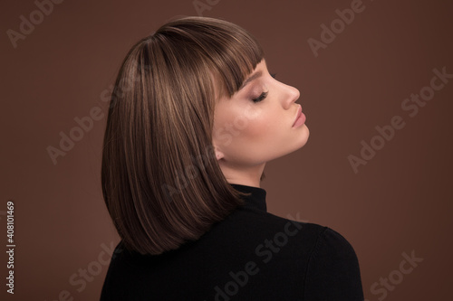 Portrait of a beautiful brown-haired woman with a short haircut on a brown background