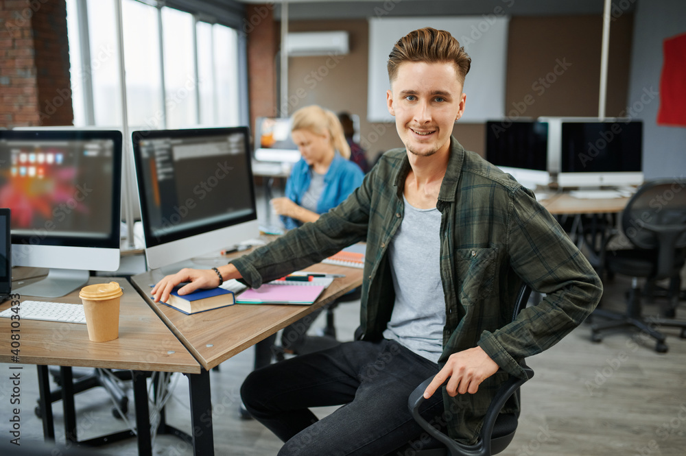 Smiling male IT specialist sits at the table Smiling male IT specialist sits at the table