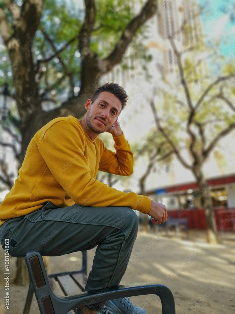 Obraz premium Man sitting on a bench in the park dressed in autumnal clothes.