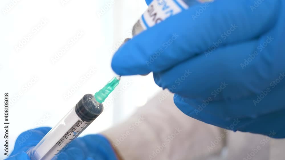 Doctor hands with blue surgical gloves holding syringe and COVID-19 vaccine. COVID-19 vaccine concept. Health and medical concept. Selective focus, Close up syringe and vaccine dose. Macro 4K video. Doctor hands with blue surgical gloves holding syringe and COVID-19 vaccine. COVID-19 vaccine concept. Health and medical concept. Selective focus, Close up syringe and vaccine dose. Macro 4K video.