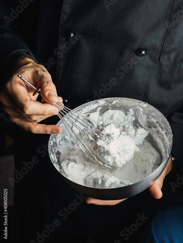  Cook in black uniform whips the cream to the point of snow Conceptual of food, gastronomy, pastry