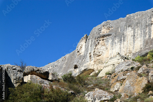 scenic limestone cliff with caves with azure sky background in Crimea