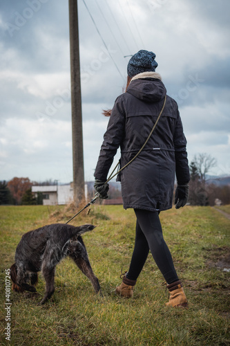 bond between dog and woman from birth. Candid portrait of a woman in winter clothes and Czech dog Bohemian Wire-haired Pointing Griffon on a wilderness walk. Binary portrait in grey moss tone © Fauren