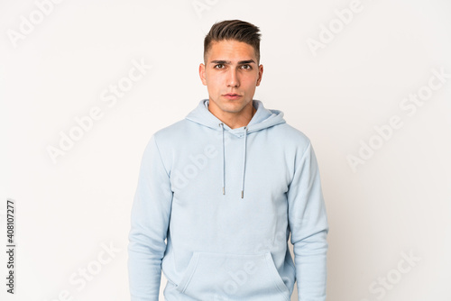 Young caucasian handsome man isolated blows cheeks, has tired expression. Facial expression concept.