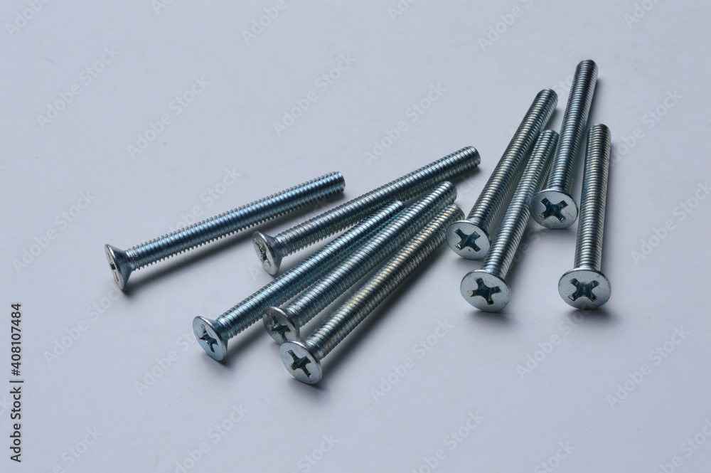 metal screws with a cross-head screwdriver slot lie on a light background. close-up. metal screws with a cross-head screwdriver slot lie on a light background. close-up.