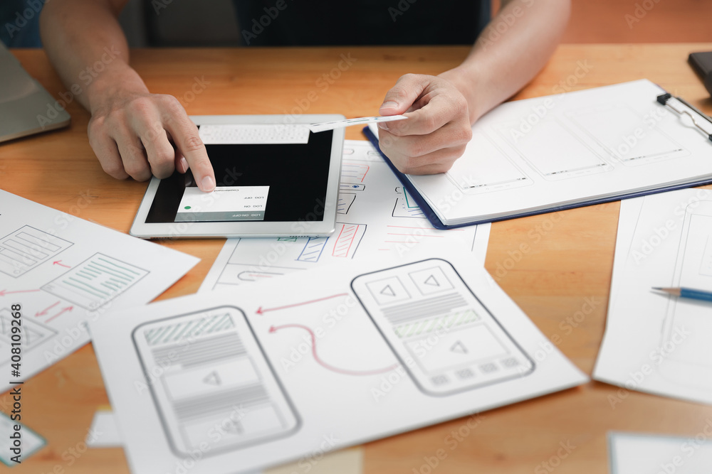 UX or UI designers designing on digital tablet and smartphone application layout prototype project. UX or UI designers designing on digital tablet and smartphone application layout prototype project.