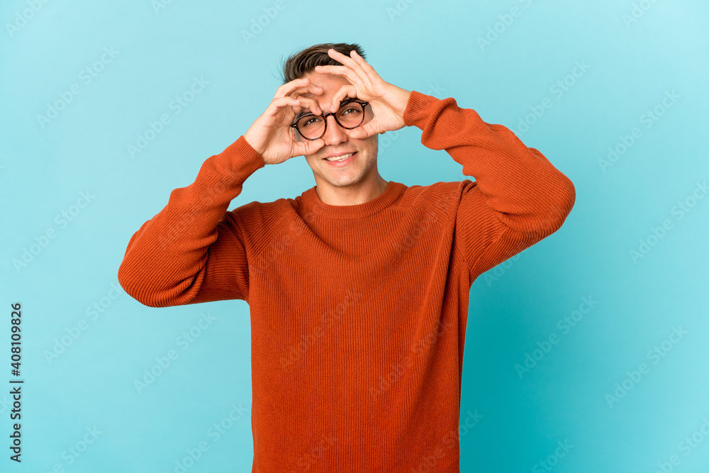 Young caucasian handsome man isolated showing okay sign over eyes Young caucasian handsome man isolated showing okay sign over eyes
