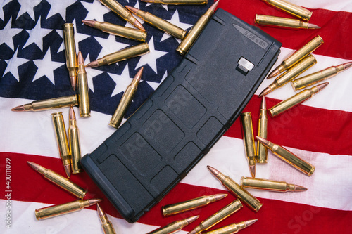 30 round bullet magazine for an AR-15 semi-auto assault rifle guns with .223 Remmington and .556 NATO ammunition behind an American flag