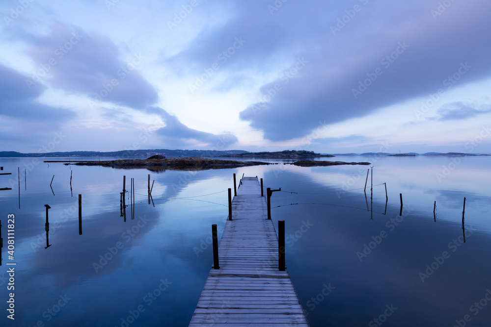 Fototapeta premium Beautiful seascape with bridge, rocky islands, and magenta clouds in a symmetrical composition on an early morning in Sweden