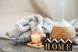A cozy home composition with an air humidifier, a set of aromatic oils and the decorative word home.