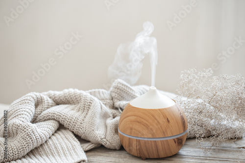Cozy home composition with air humidifier, knitted element and dried flowers copy space.