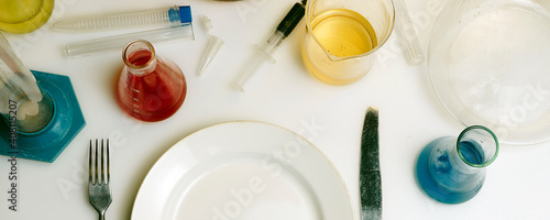 Plate, fork and knife on a laboratory table. Food chemistry concept.