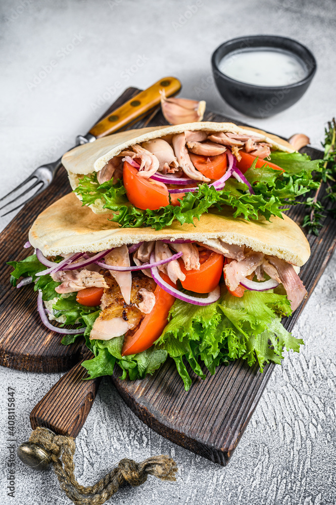 Pita sandwich with roasted chicken, vegetables and delicious sauce. White background. Top view