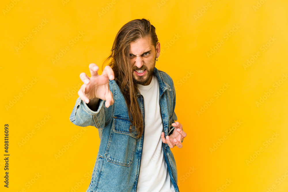 Young man with long hair look showing claws imitating a cat, aggressive gesture. Young man with long hair look showing claws imitating a cat, aggressive gesture.