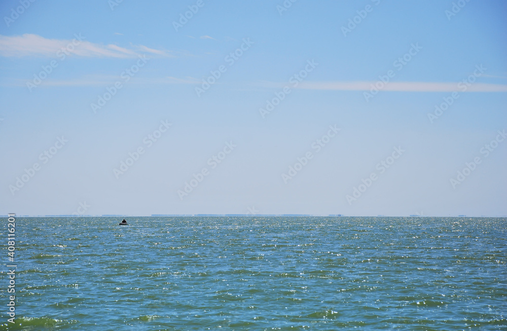 Fototapeta premium Blue sea and sky, silhouette of fishermen with his boat, small fishing boat in beautiful blue sea water