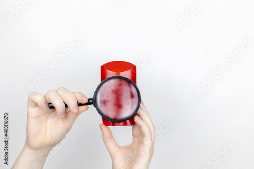 A woman is holding antiperspirant, examines the composition under a magnifying glass. Place for your text. The concept of hazardous substances in cosmetics and household chemicals photo