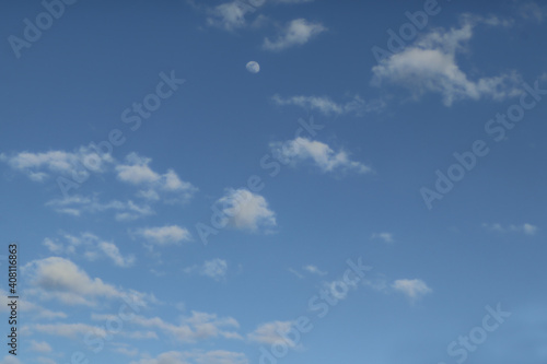 Blue sky with fluffy clouds and partial moon - background or replacement.