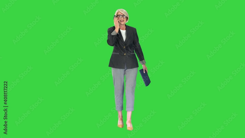 Senior businesswoman making a call while walking on a Green Screen, Chroma Key. Senior businesswoman making a call while walking on a Green Screen, Chroma Key.