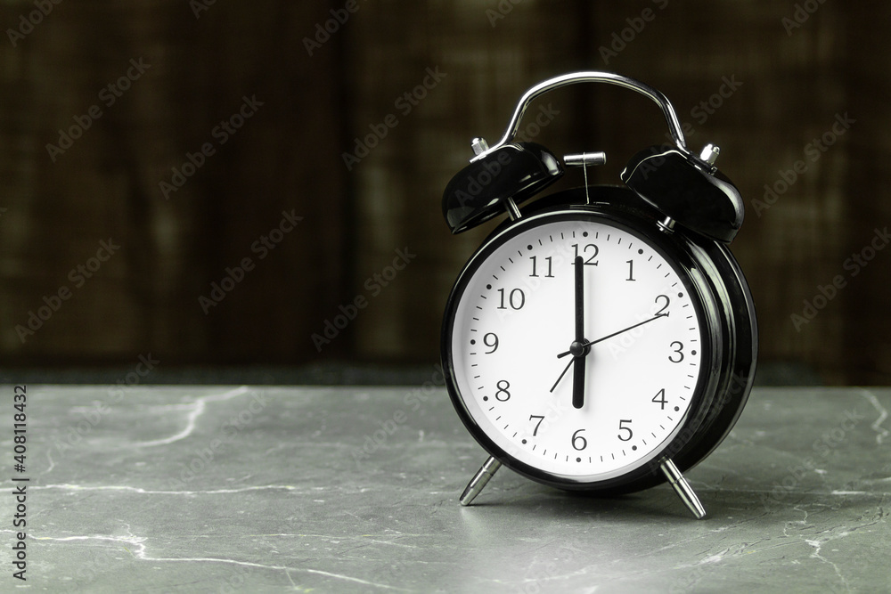 The black alarm clock hands point to six o'clock The black alarm clock hands point to six o'clock