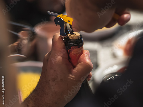 Manos ancianas descorchando una botella de vino