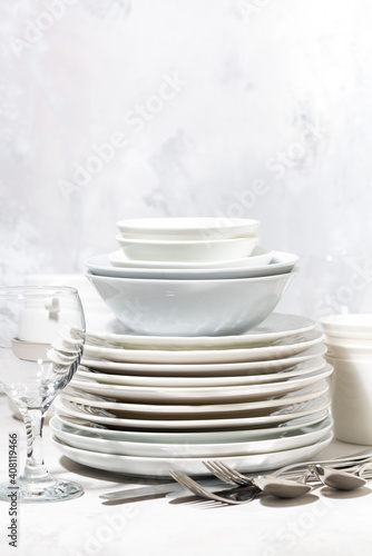 tableware, cutlery and glasses on a white table, vertical