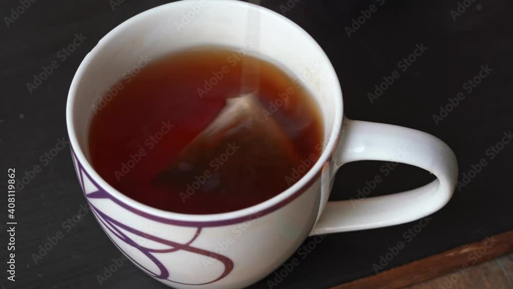 hand dips a tea bag into a cup of tea hand dips a tea bag into a cup of tea