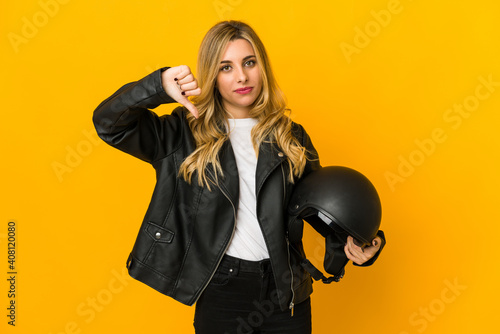 Young blonde caucasian biker woman holding helmet showing a dislike gesture, thumbs down. Disagreement concept.
