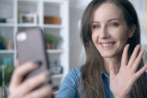 Happy white woman smiling, using phone, having video call, video chatting at home or in the office.