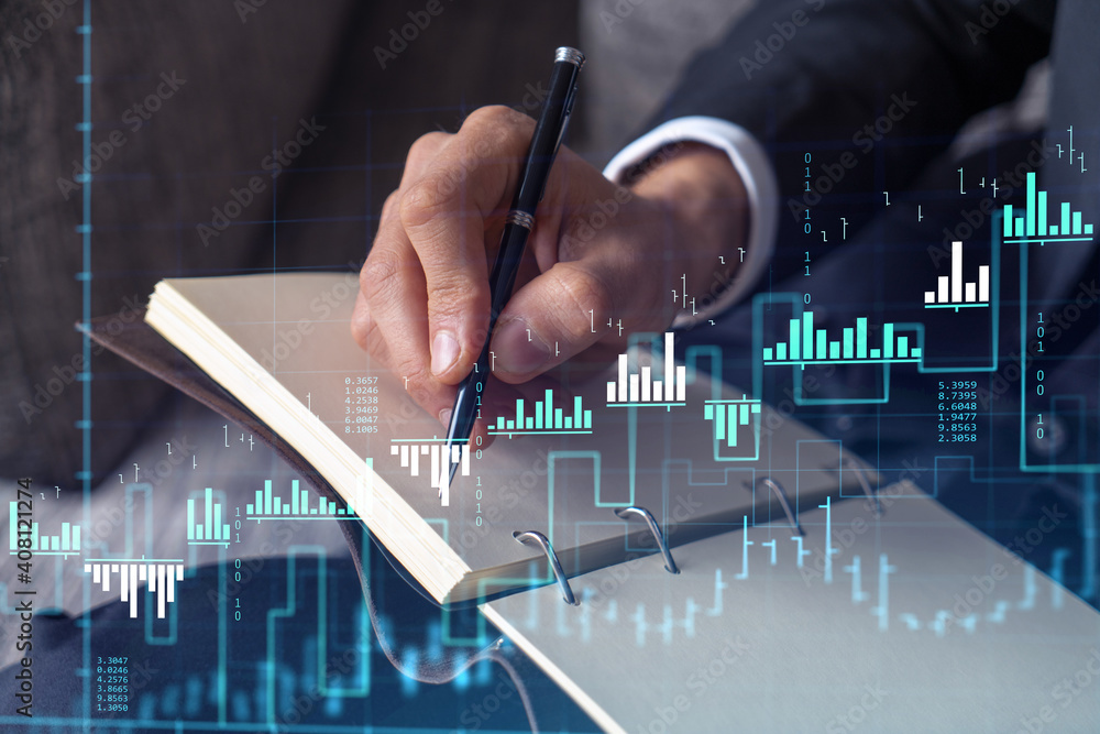 Fototapeta premium A trader in formal wear writing down some ideas to research stock market to proceed right investment solutions. Wealth management concept. Hologram Forex chart over close up shot.