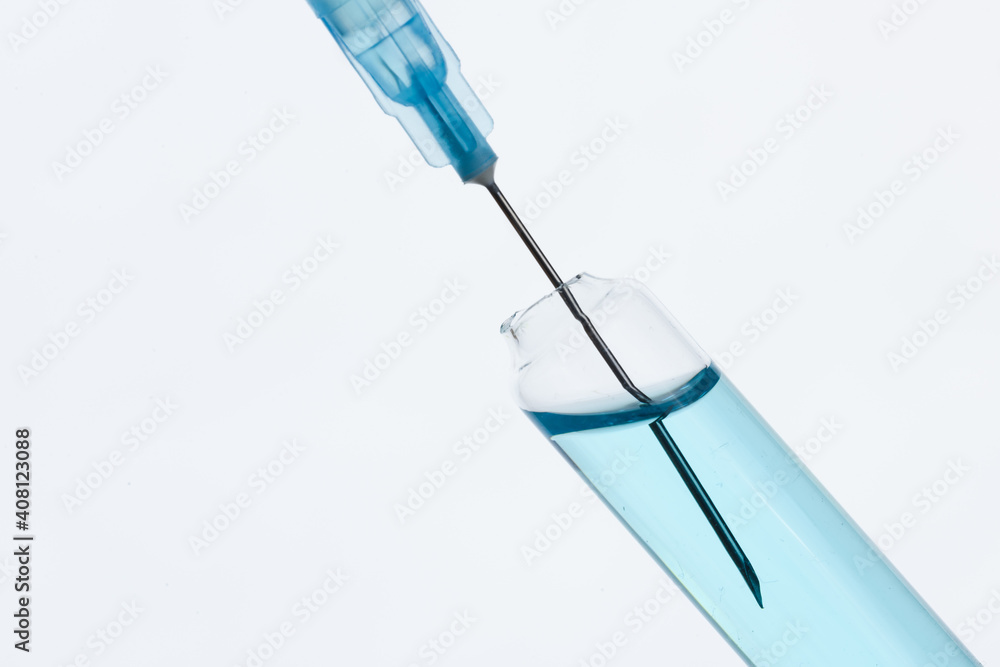 The syringe draws the blue vaccine from a medical bottle. On gray. The syringe draws the blue vaccine from a medical bottle. On gray.