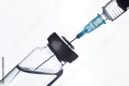 A syringe draws a vaccine from a medical bottle. On white.