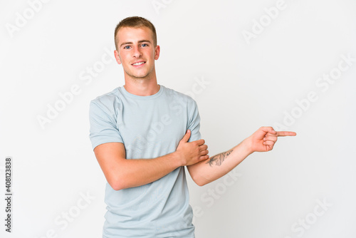 Young caucasian handsome man smiling cheerfully pointing with forefinger away.