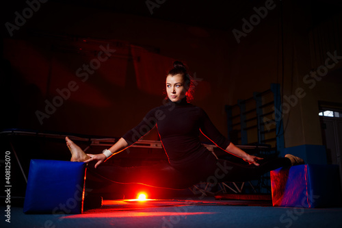 Young woman practices twine sitting. Athletic girl doing gymnastics in the gym. Active lifestyle