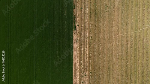 Top down drone shot over two fields, one with grass and the other empty. 4k