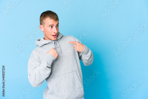 Young caucasian handsome man surprised pointing with finger, smiling broadly.