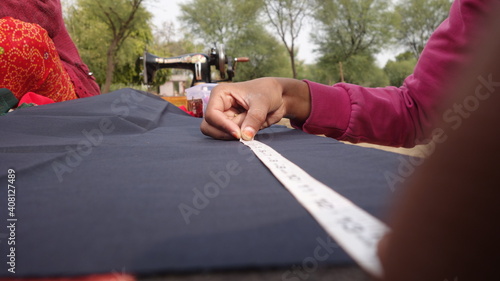 Young Girl measuring on the clothes with plastic strip. Woman tailor working on new clothing. Rajasthan, India - 4 January, 2020;