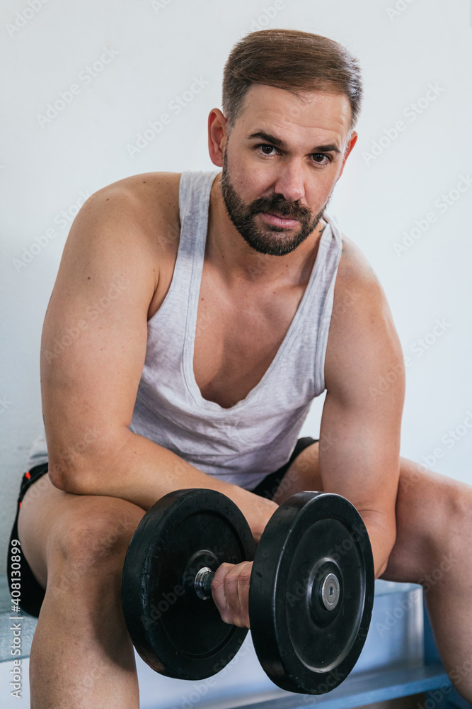 Man doing biceps exercises with dumbbells at the gym. sitting on a bench. health and wellness concept. Man doing biceps exercises with dumbbells at the gym. sitting on a bench. health and wellness concept.