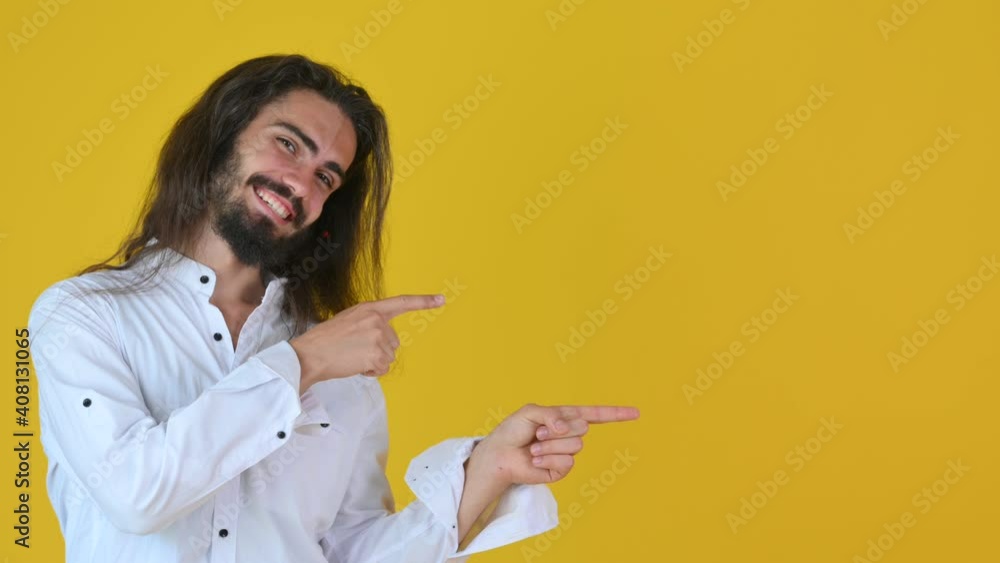 Happy young guy Look camera pointing fingers hands on copy space workspace isolated on yellow studio background. People lifestyle concept. Happy young guy Look camera pointing fingers hands on copy space workspace isolated on yellow studio background. People lifestyle concept.