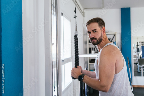 A man doing triceps exercises in the gym. Looking at the camera. Health and wellness concept.